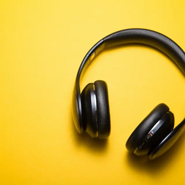 Black over-ear headphones on a yellow backdrop